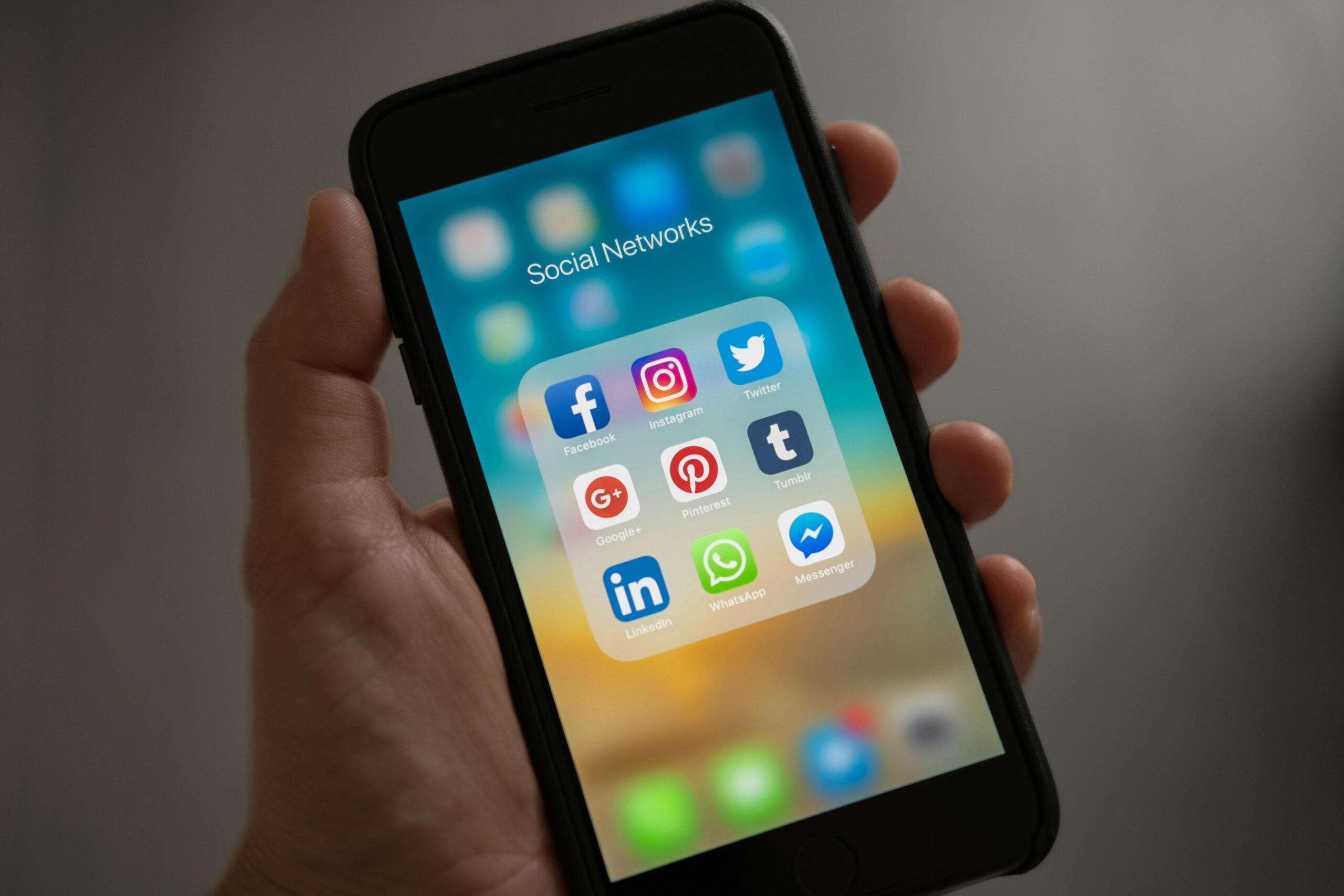Person holding iphone showing social networks folder